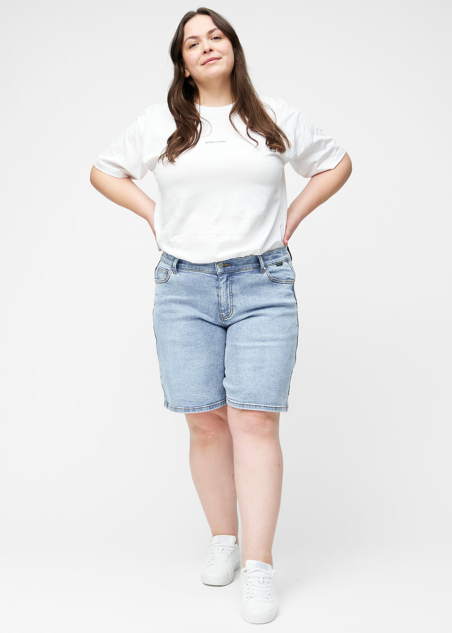 Plus-size model viser lyseblå denim shorts til kvinder i farven Waves med loose pasform i bevægelse.