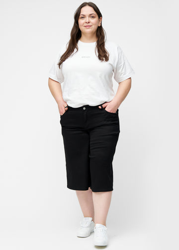 Plus-size model viser løse, sorte capris i farven Ravens i bevægelse og demonstrerer pasform og materiale.