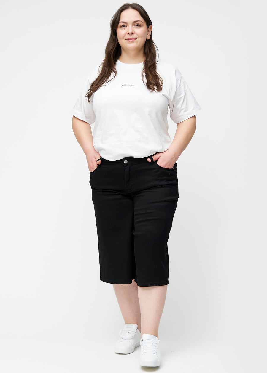 Plus-size model viser løse, sorte capris i farven Ravens i bevægelse og demonstrerer pasform og materiale.